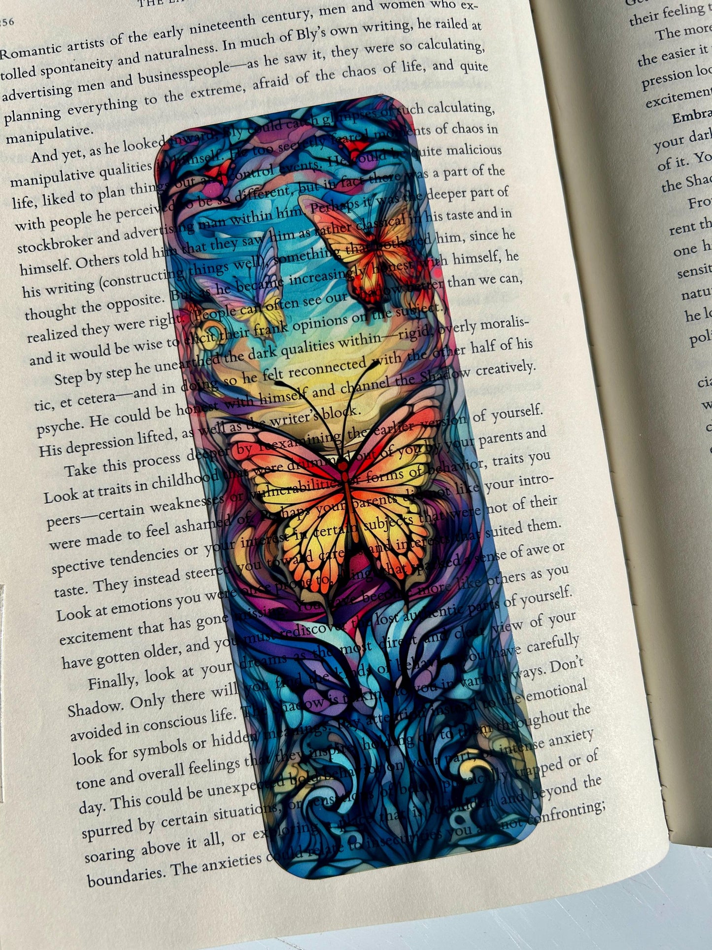 Stained glass butterfly bookmark in radiant sunset hues, vivid colors with floral accents, vibrant fantasy nature bookmark